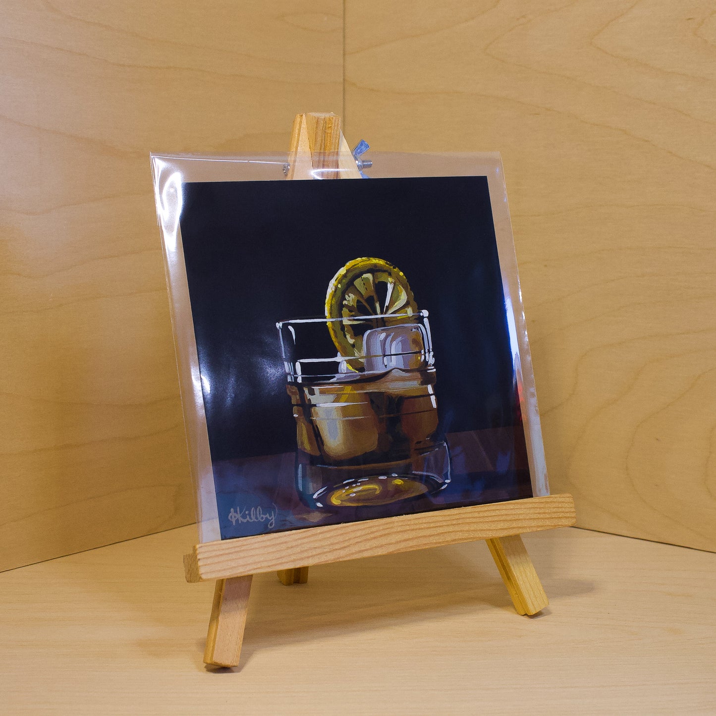 A 6x6" fine art print of the original acrylic painting "Old Fashioned" by Hannah Kilby from Hannah Michelle Studios. Displayed in a protective plastic sleeve on a small, wooden easel.