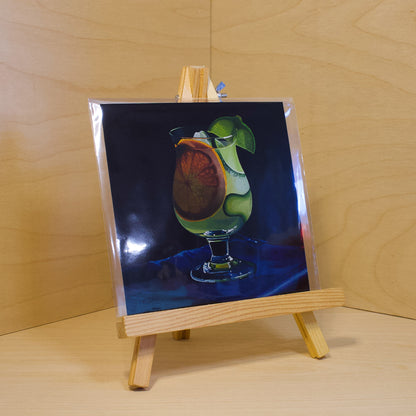 A 6x6" fine art print of the original acrylic painting "Gin & Tonic" by Hannah Kilby from Hannah Michelle Studios. Displayed in a protective plastic sleeve on a small, wooden easel.