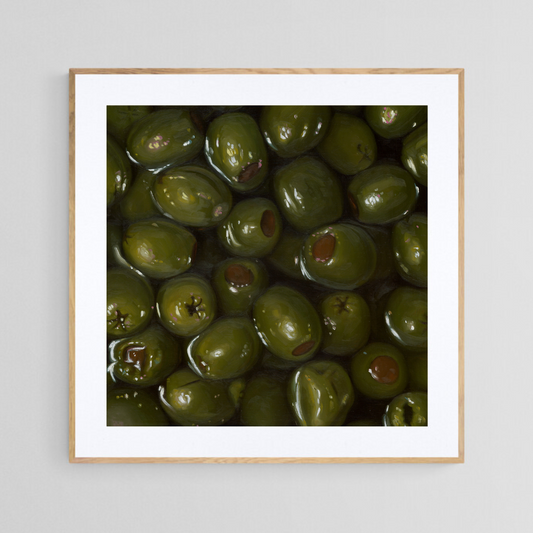 The original painting “Green Olives" by Hannah Kilby from Hannah Michelle Studios, displayed as a 12x12" fine art print in a 16x16" oak frame.