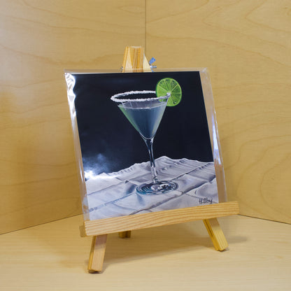 A 6x6" fine art print of the original acrylic painting "Margarita" by Hannah Kilby from Hannah Michelle Studios. Displayed in a protective plastic sleeve on a small, wooden easel.