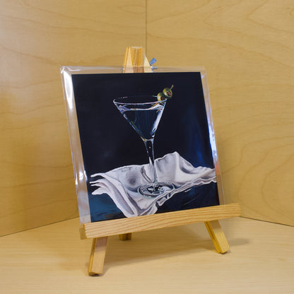 A 6x6" fine art print of the original acrylic painting "Martini" by Hannah Kilby from Hannah Michelle Studios. Displayed in a protective plastic sleeve on a small, wooden easel.