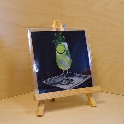 A 6x6" fine art print of the original acrylic painting "Mojito" by Hannah Kilby from Hannah Michelle Studios. Displayed in a protective plastic sleeve on a small, wooden easel.